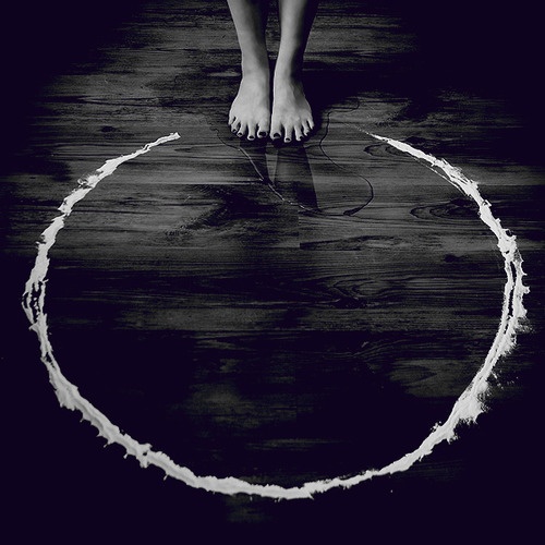 bare feet standing at the edge of a white circle on the ground